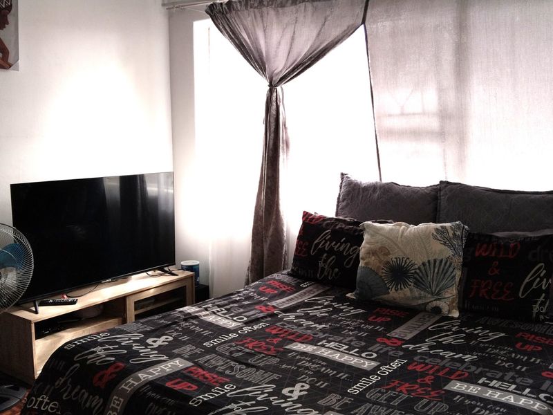 A bedroom featuring natural light through window curtains, providing a functional space for rest.