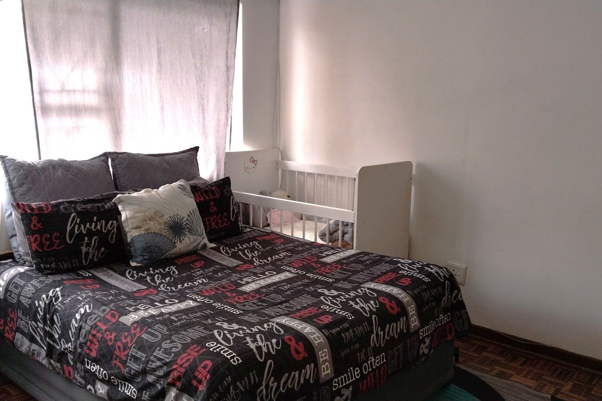 A bedroom featuring parquet flooring and a window with a curtain rail, providing a functional space for rest.