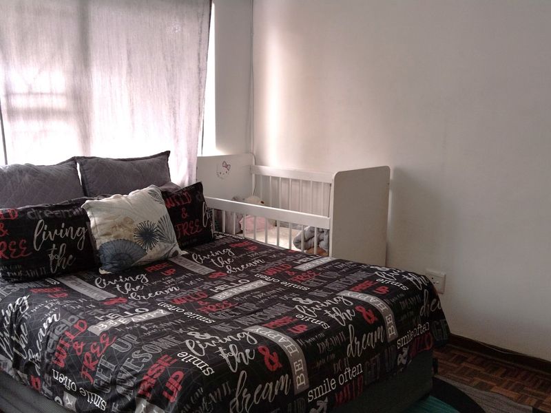 A bedroom featuring parquet flooring and a window with a curtain rail, providing a functional space for rest.