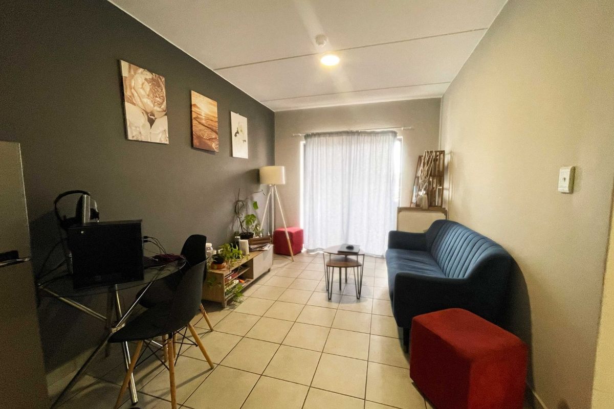 A living room featuring tiled flooring and a sliding glass door providing natural light.