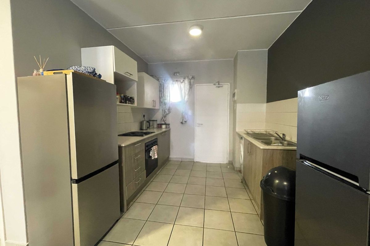 A functional kitchen featuring built-in cabinetry, laminate countertops, a built-in oven with electric hob, and tiled flooring throughout.