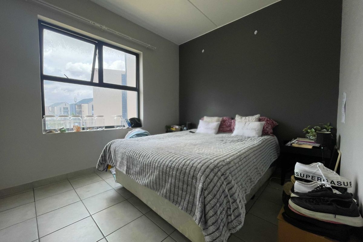 A bedroom featuring tiled flooring, a large window providing natural light, and a dark accent wall.