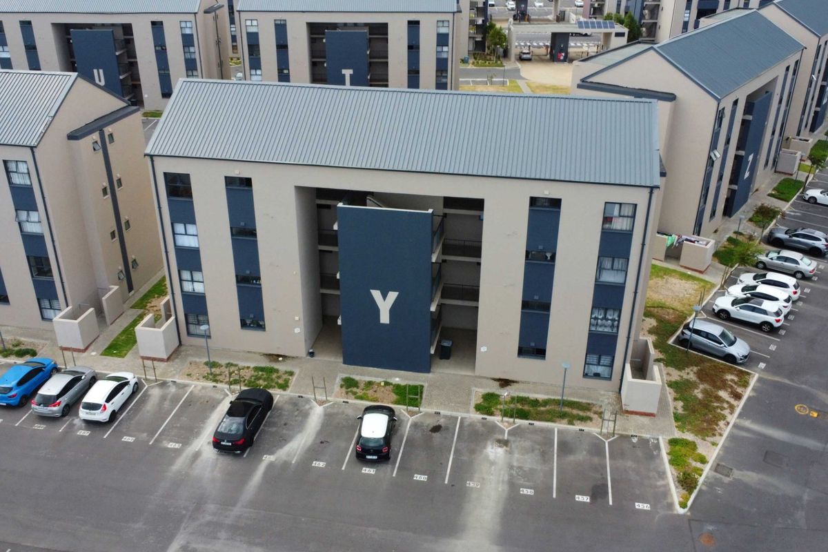 Aerial view of a modern multi-story apartment complex featuring designated paved parking bays and contemporary architectural design.