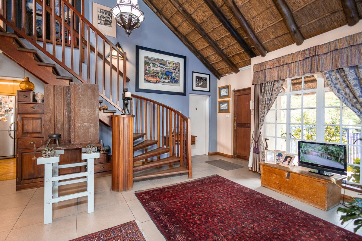 Spacious living area featuring a unique spiral timber staircase, exposed thatched ceiling with timber rafters, and tiled flooring with natural light.