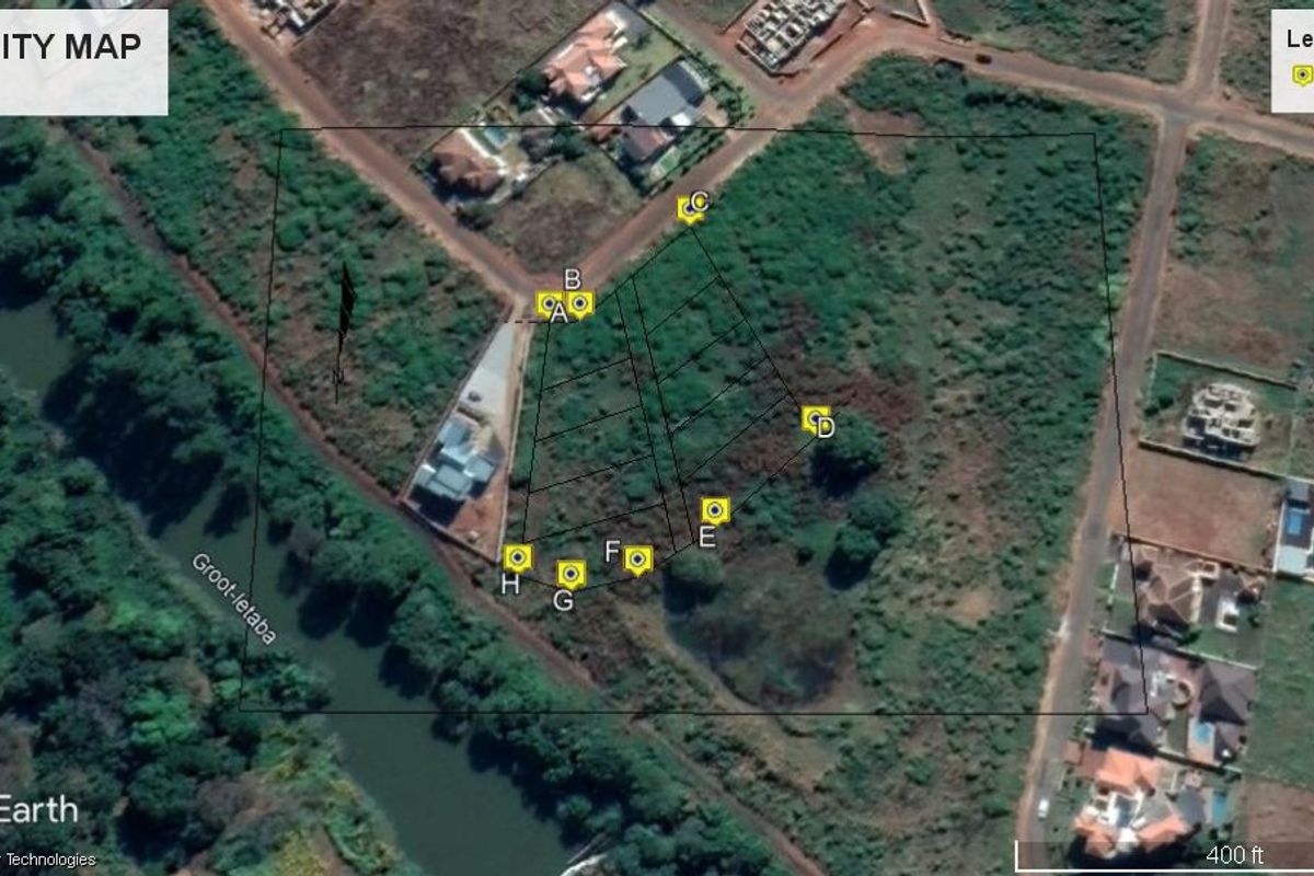 Aerial view of a vacant residential plot featuring river frontage and marked boundary points.