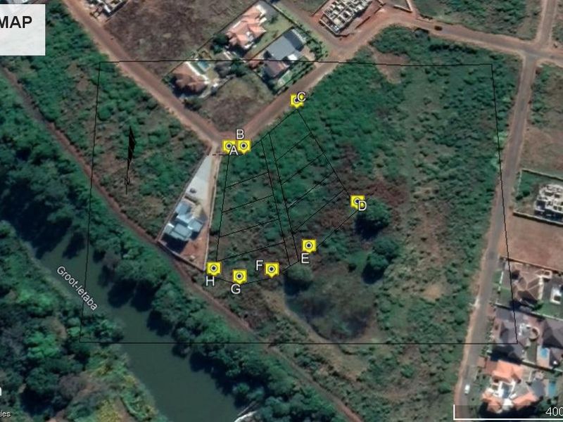Aerial view of a vacant residential plot featuring river frontage and marked boundary points.