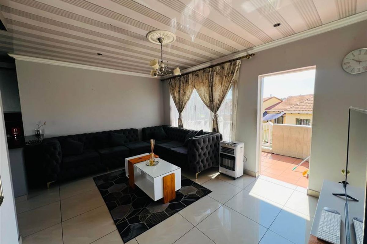 A living room featuring tiled flooring, a decorative ceiling rose, and direct access to an outdoor balcony area.