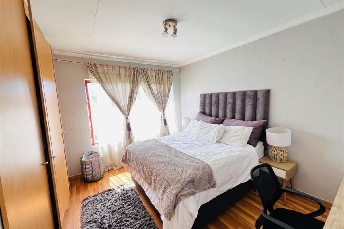 A bedroom featuring laminate flooring and a built-in wardrobe, offering a functional space with natural light.