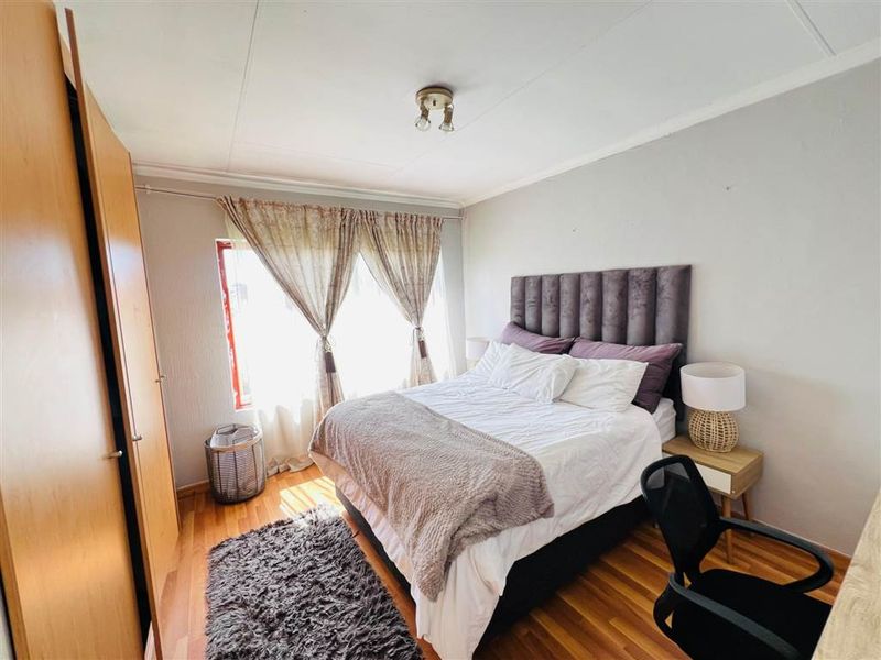 A bedroom featuring laminate flooring and a built-in wardrobe, offering a functional space with natural light.