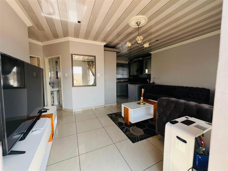 Open plan living area featuring tiled flooring and a connected kitchen space with built-in cabinetry.