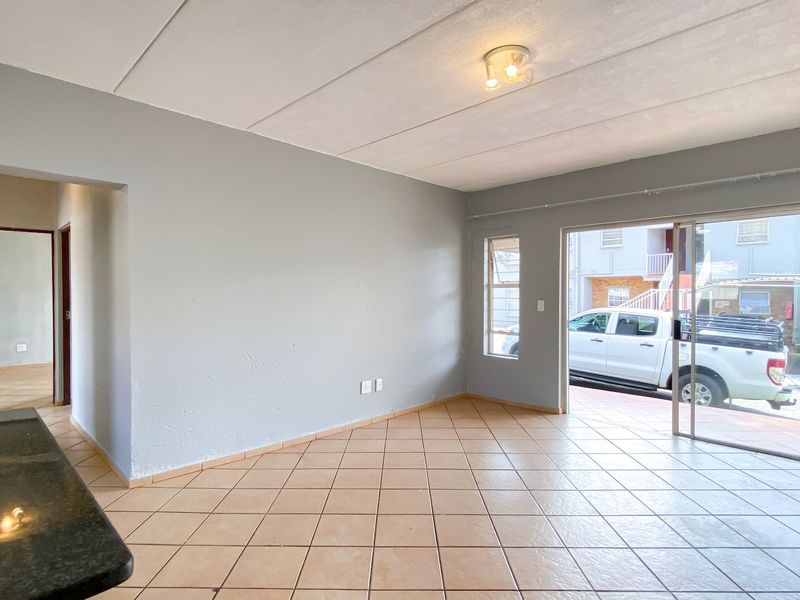 An open-plan living area featuring tiled flooring, a granite breakfast bar, and a sliding glass door providing access to the exterior.
