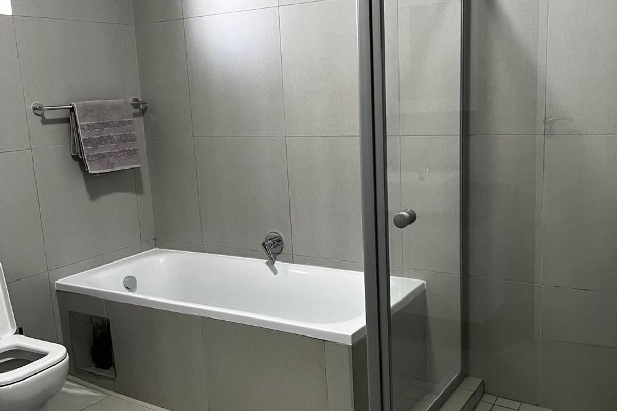 Modern bathroom featuring a tiled bathtub, separate glass-enclosed shower, and neutral wall tiling.