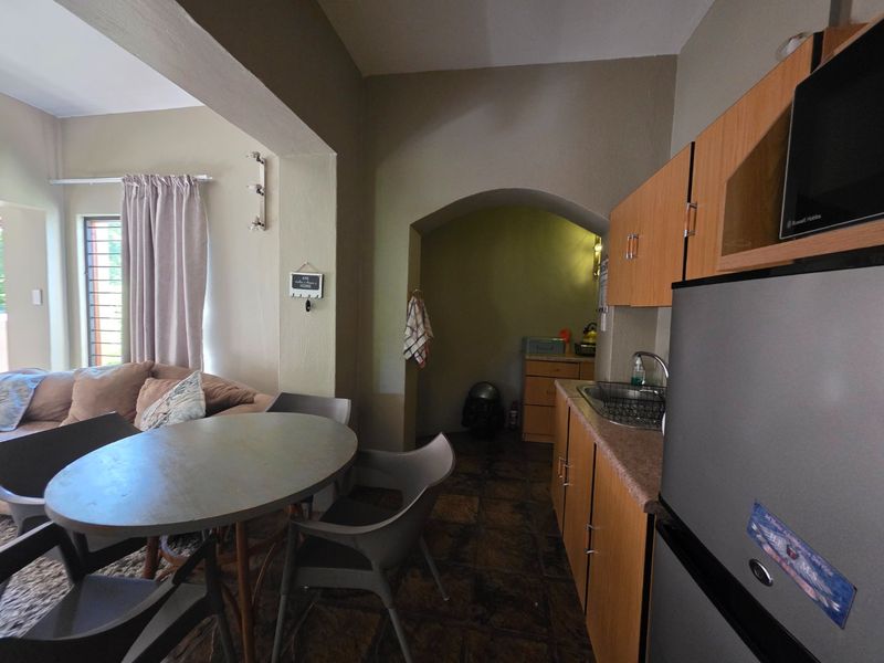 Open plan living area featuring a compact kitchen with built-in cabinetry, laminate countertops, and a tiled floor, seamlessly connected to the dining space.