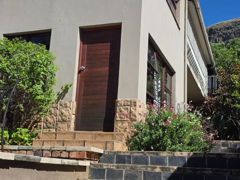 Exterior view of the apartment entrance featuring stone cladding, a solid timber door, and tiled steps leading to the main access point.