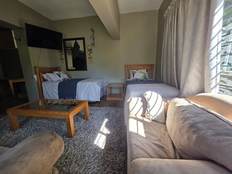 A bedroom featuring neutral wall tones, natural light through window treatments, and space for twin beds.