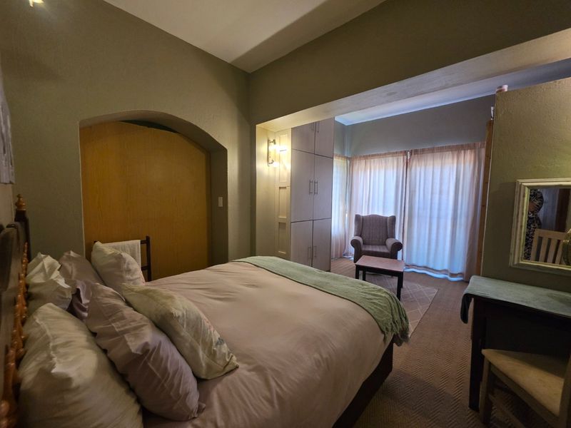 A spacious bedroom featuring built-in cupboards, an architectural archway, and sliding glass doors that provide access to natural light.