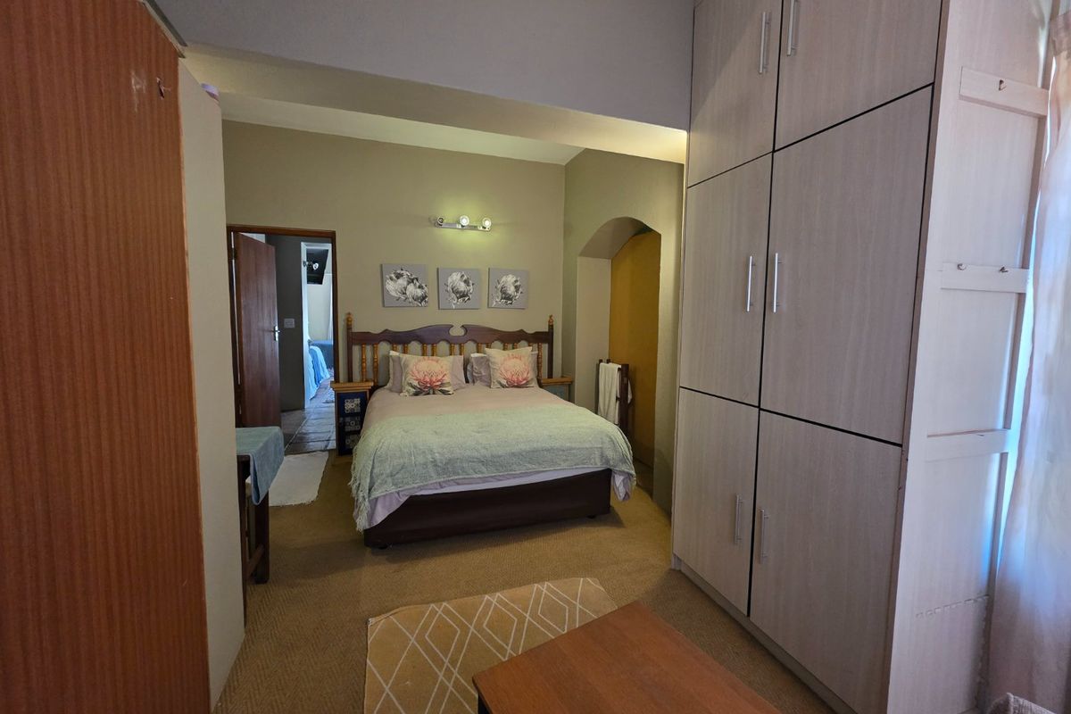 A bedroom featuring built-in cupboards, neutral wall tones, and an arched architectural detail, providing a functional and comfortable sleeping space.