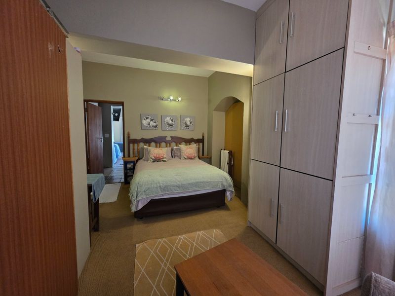 A bedroom featuring built-in cupboards, neutral wall tones, and an arched architectural detail, providing a functional and comfortable sleeping space.