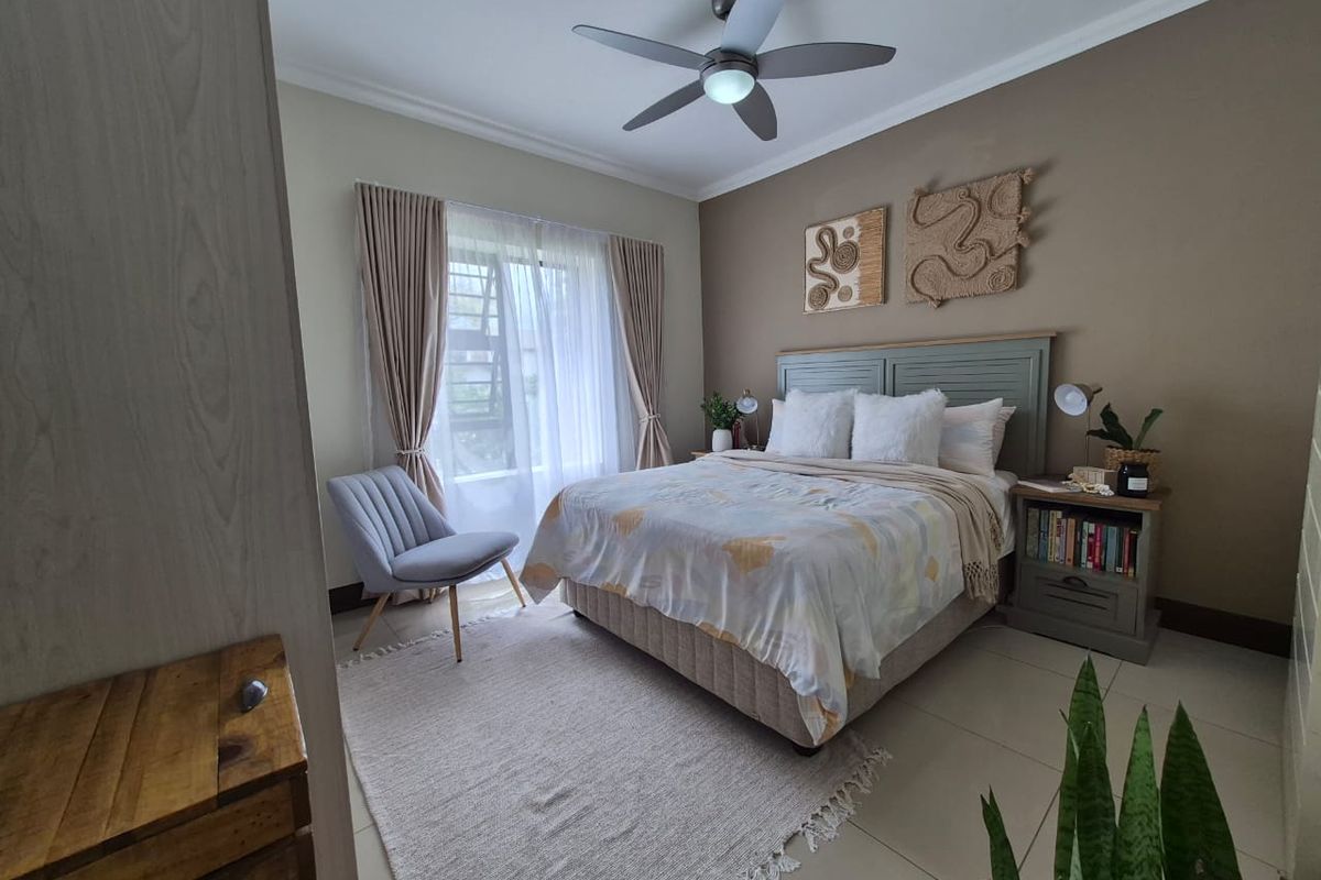 A well-maintained bedroom featuring tiled flooring, a ceiling fan, and built-in cupboard storage with neutral wall finishes.