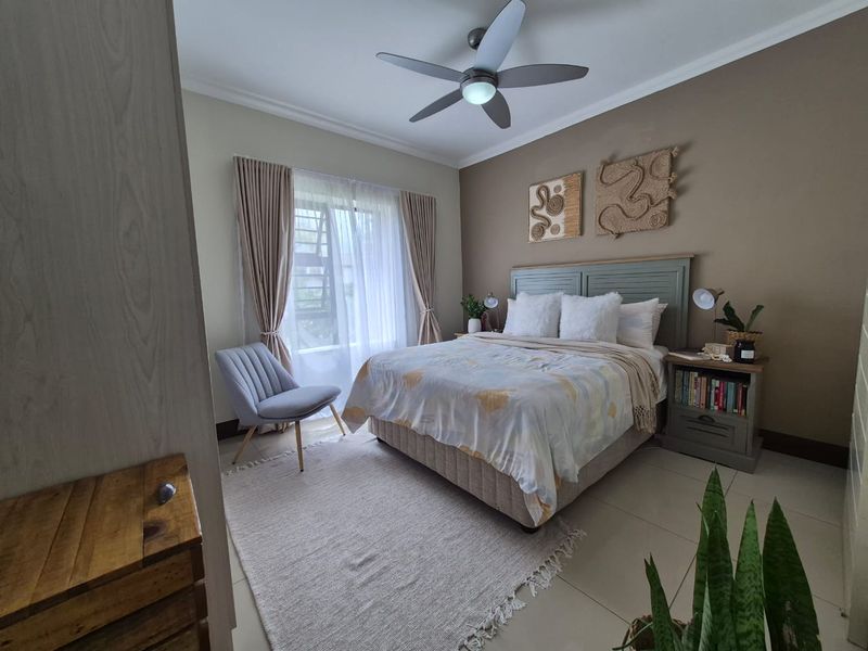 A well-maintained bedroom featuring tiled flooring, a ceiling fan, and built-in cupboard storage with neutral wall finishes.