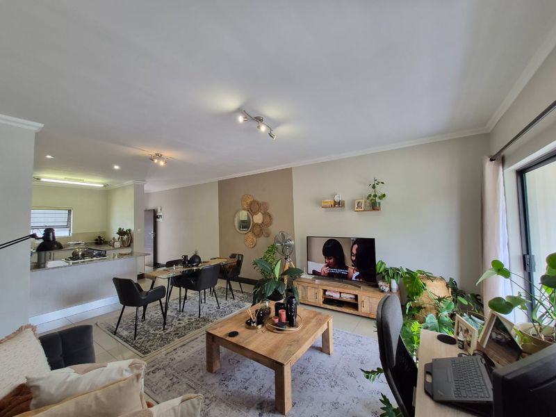 Spacious open-plan living and dining area featuring a modern kitchen island, neutral wall finishes, and large sliding glass doors providing natural light.