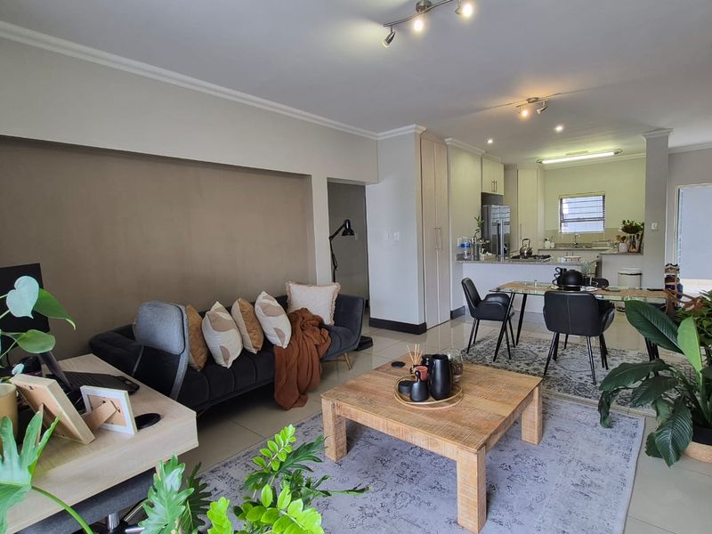 An open-plan living and dining area featuring tiled floors, recessed lighting, and a functional kitchen with built-in cabinetry and a breakfast island.