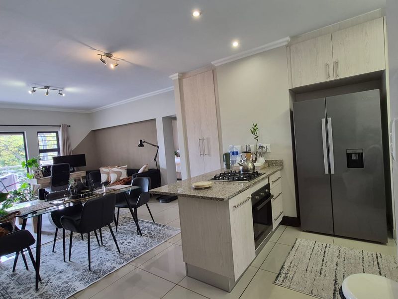 Open-plan living area featuring a modern kitchen with granite countertops, gas hob, built-in oven, and ample cabinetry, seamlessly flowing into the dining and lounge space.
