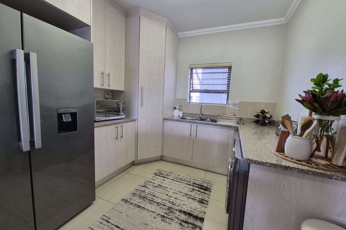 A well-maintained kitchen featuring light wood-grain cabinetry, granite countertops, and tiled flooring, providing a clean and functional workspace.