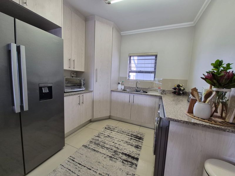A well-maintained kitchen featuring light wood-grain cabinetry, granite countertops, and tiled flooring, providing a clean and functional workspace.