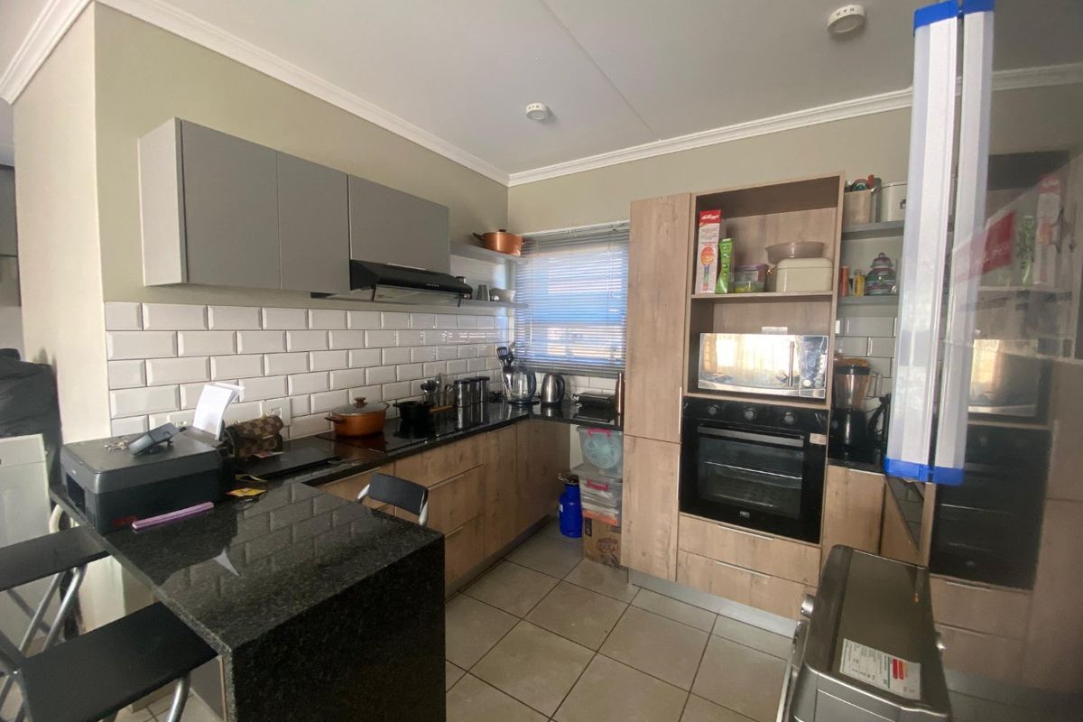 Modern kitchen featuring granite countertops, subway tile backsplash, built-in oven, extractor fan, and a functional breakfast bar with ample cabinetry.