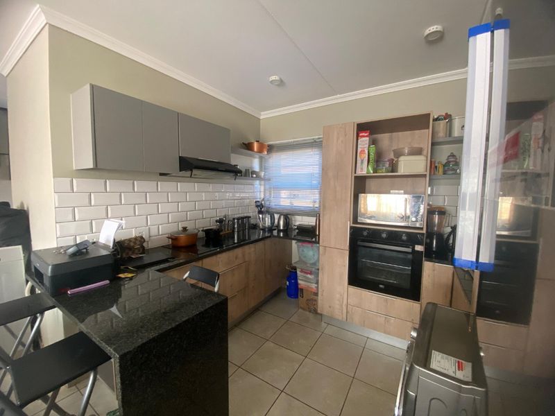 Modern kitchen featuring granite countertops, subway tile backsplash, built-in oven, extractor fan, and a functional breakfast bar with ample cabinetry.