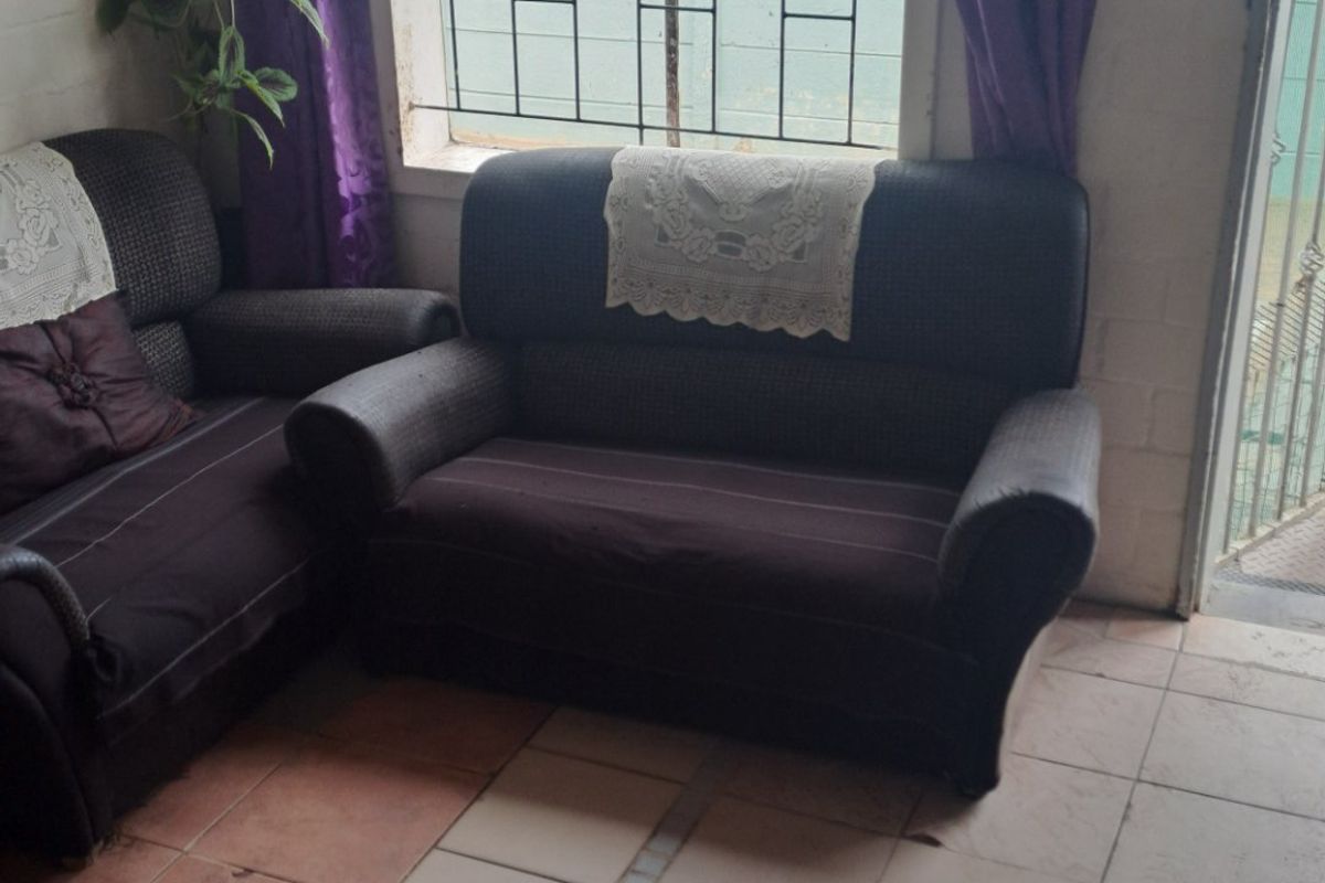 Living room area featuring tiled flooring with visible damage and security bars on the window.