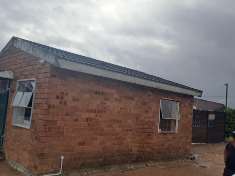 A single-story face brick house featuring a pitched roof and casement windows, showing signs of exterior wear and maintenance requirements.