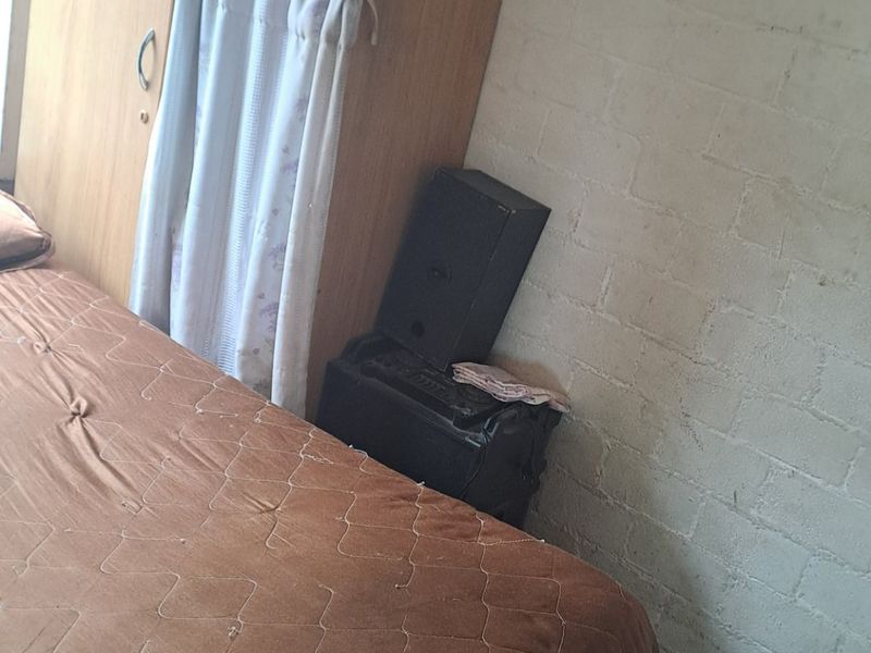 A bedroom featuring an exposed brick wall and a built-in wooden wardrobe with overhead storage.