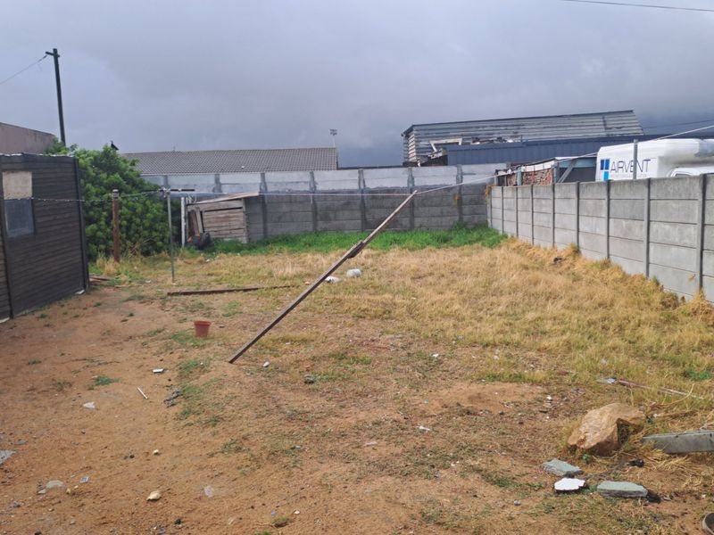 A rear yard area featuring a precast concrete boundary wall and a timber shed, requiring landscaping and site clearance.