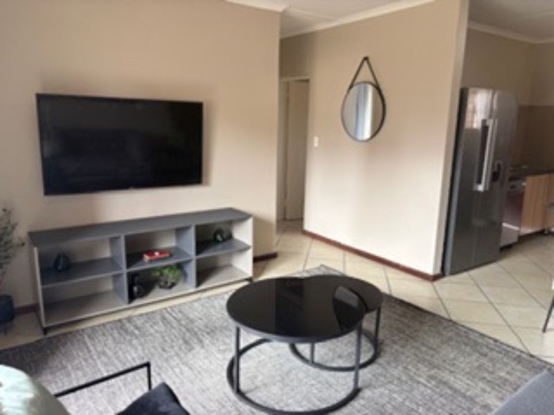 An open-plan living area featuring neutral wall tones, ceramic floor tiles, and a coved ceiling, seamlessly connecting to the adjacent kitchen space.