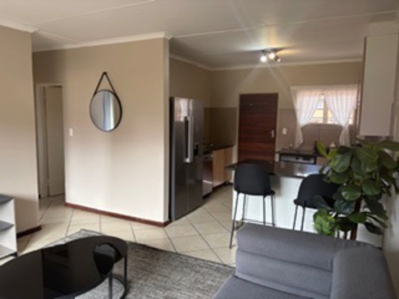 Open plan living area featuring a functional kitchen with breakfast bar, granite countertops, and tiled flooring throughout.