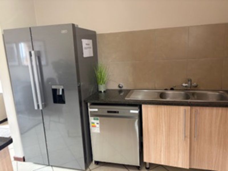 A functional kitchen area featuring a double sink, granite countertops, tiled backsplash, and built-in cabinetry.