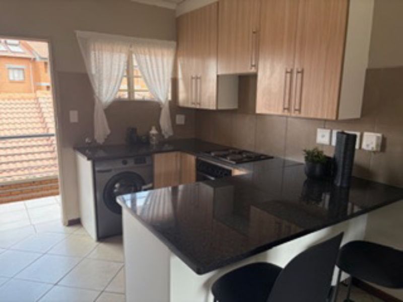 Functional kitchen featuring light wood cabinetry, dark granite countertops, a breakfast nook, and built-in oven and hob, with direct access to a balcony.