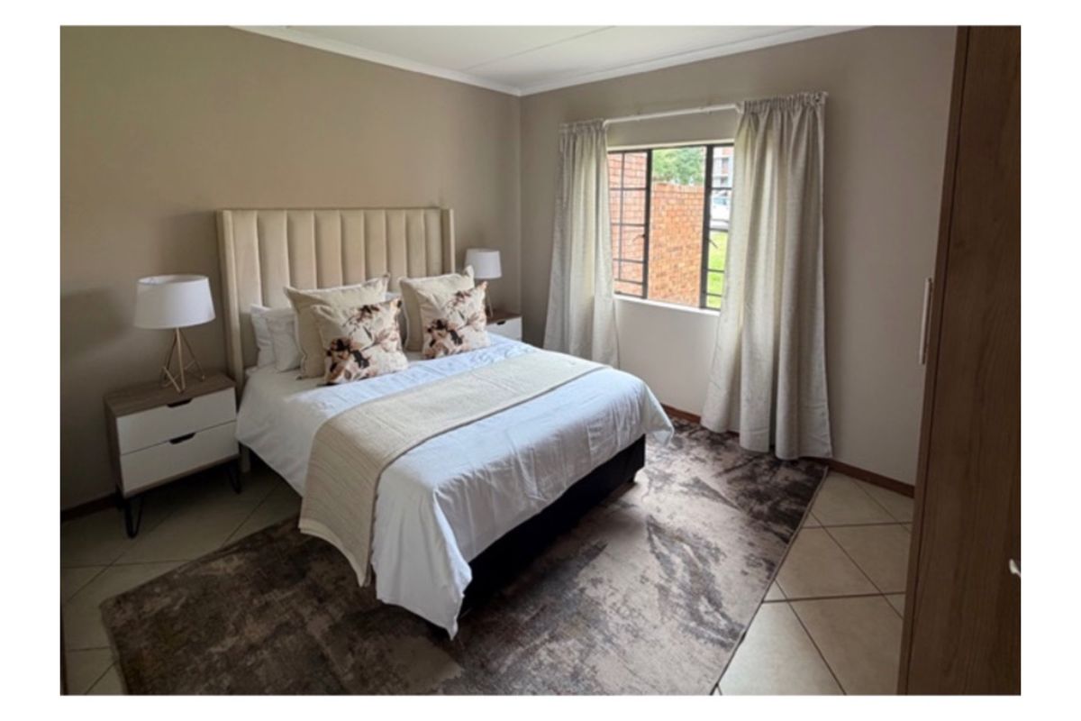 A well-maintained bedroom featuring neutral wall tones, tiled flooring, and a built-in wardrobe, offering a comfortable and functional living space.