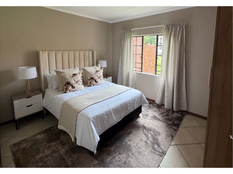A well-maintained bedroom featuring neutral wall tones, tiled flooring, and a built-in wardrobe, offering a comfortable and functional living space.