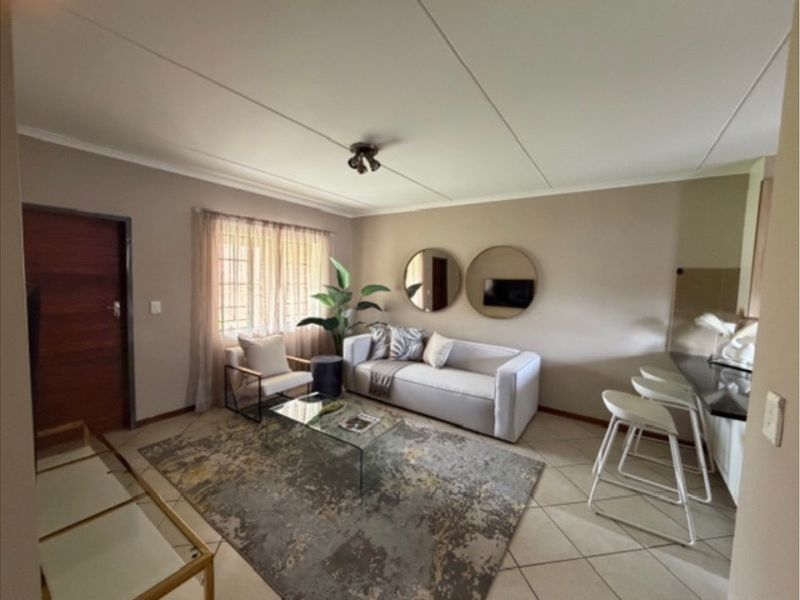 Open-plan living area featuring tiled flooring, a breakfast bar, and neutral wall tones, creating a functional and connected space.