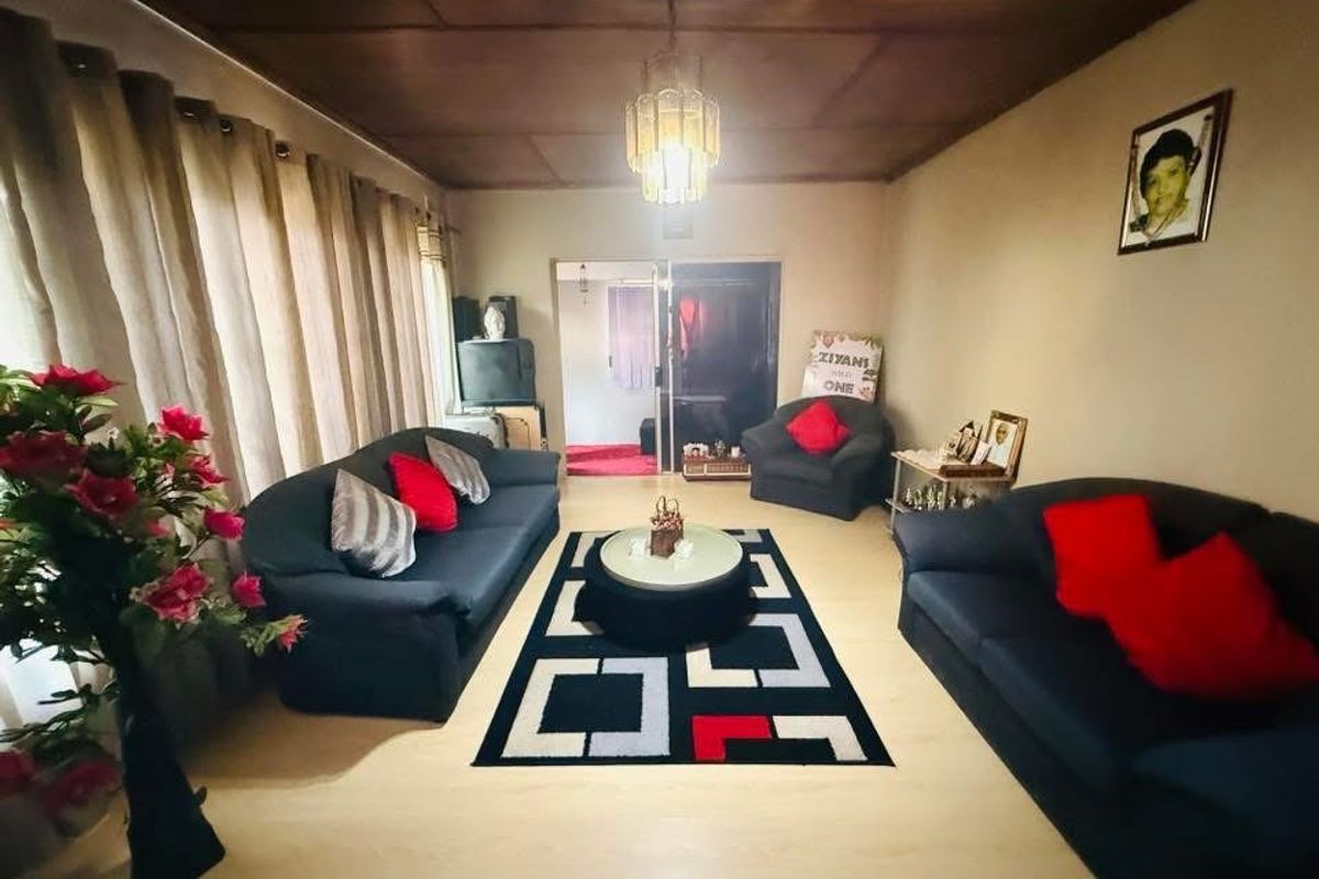 A living room featuring laminate flooring and a timber ceiling, providing a functional space with access to an adjoining room via a sliding door.