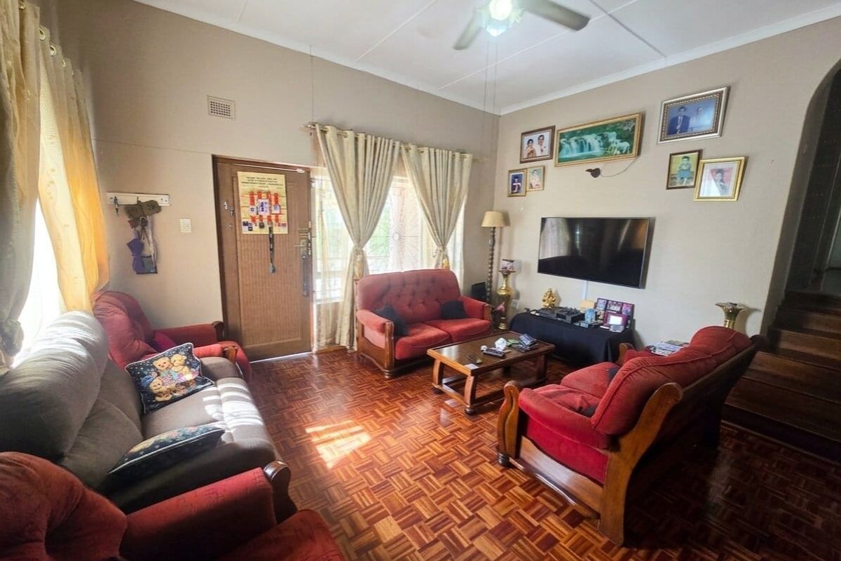 A living room featuring traditional parquet flooring, a ceiling fan, and direct access to the exterior via a timber door.