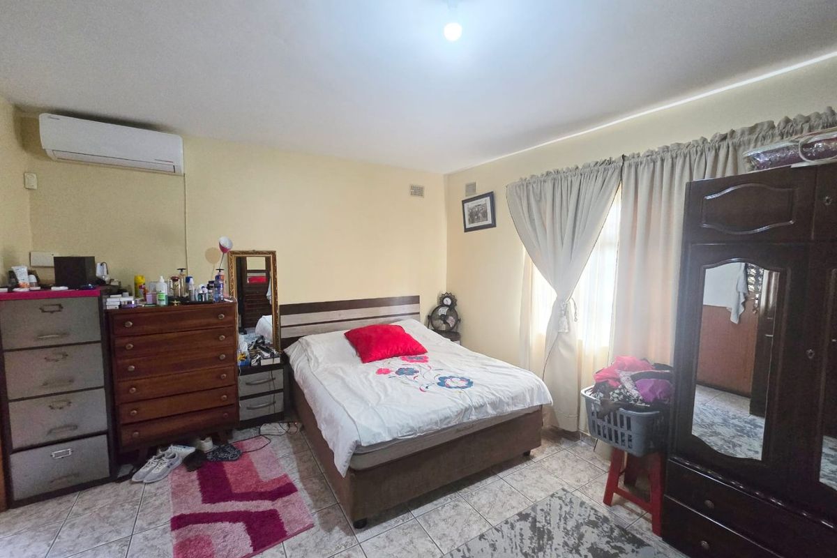A functional bedroom featuring tiled flooring and a wall-mounted split-system air conditioner, providing a comfortable and climate-controlled living space.