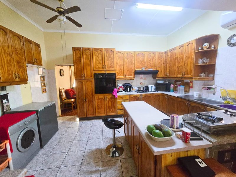 Spacious kitchen featuring extensive wooden cabinetry, a central island, built-in oven, and tiled flooring, offering a functional layout with ample storage space.