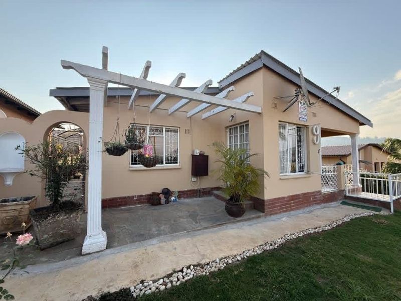 Front elevation of a single-story house featuring a covered patio with a pergola, security gates, and a small garden area.
