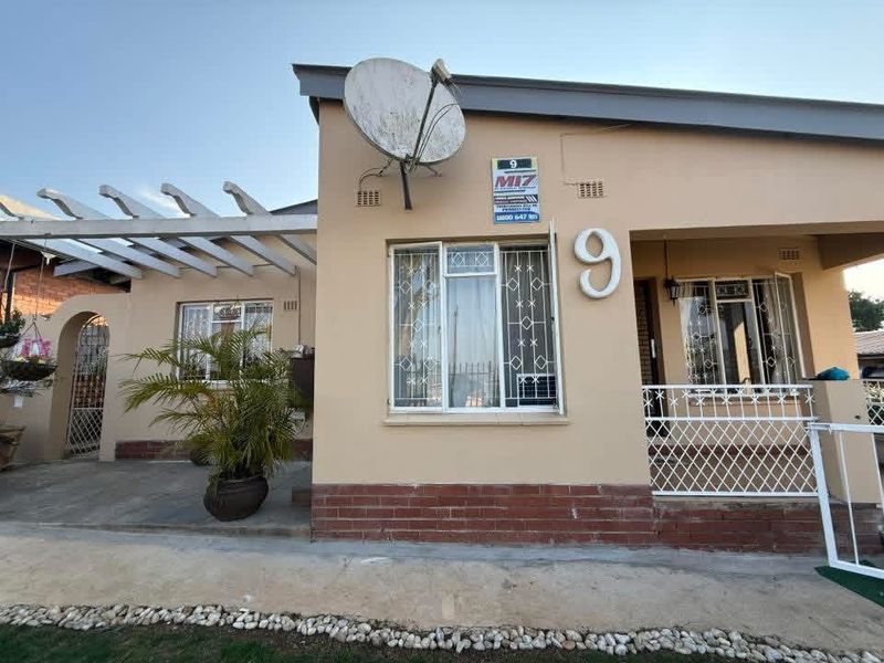 Front facade of a single-story house featuring a pergola, security bars on windows, and a brick plinth base.