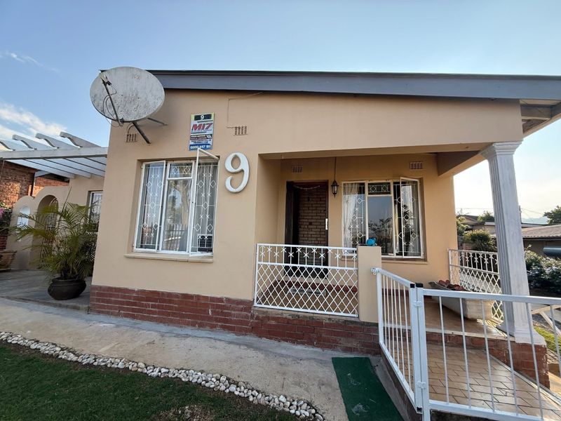 Front facade of a single-story house featuring a covered porch, security gates, burglar bars, and a satellite dish installation.