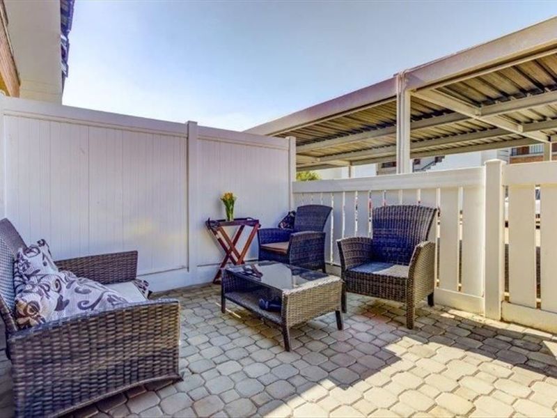 A private outdoor patio area featuring paved flooring and vinyl privacy fencing, adjacent to a covered carport structure.